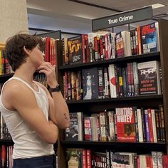 a man standing in front of a bookshelf talking on a cell phone