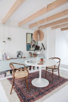 a white table and chairs in a room with wooden beams on the ceiling above it