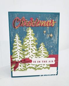 a christmas card with snow covered trees and the words, christmas is in the air