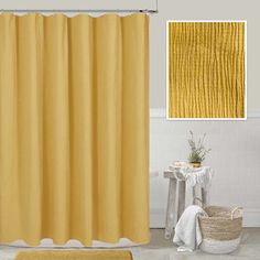 a yellow shower curtain in a bathroom next to a white rug and basket on the floor