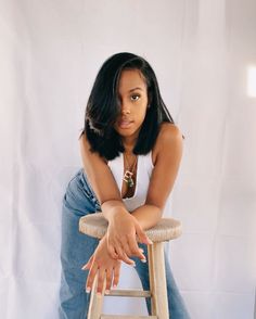 a woman sitting on top of a wooden stool