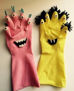 two gloves with monster faces on them are hanging from the wall, and one is made out of paper