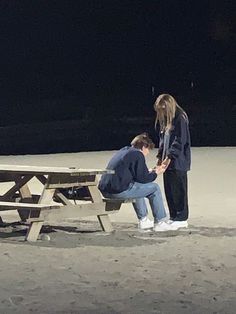 two people sitting at a picnic table in the dark