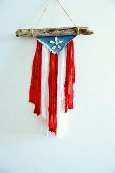 a red, white and blue flag hanging from a wooden stick with flowers on it