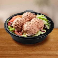 a salad in a black bowl on a wooden table