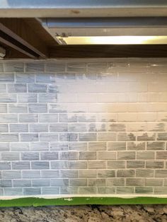 a kitchen counter with white tiles and green grouting on the backsplash