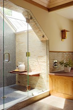 a bathroom with a glass shower door and tiled walls, along with a skylight