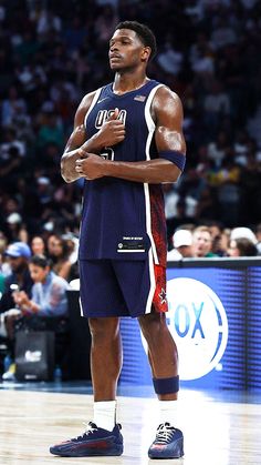 a basketball player standing on the court with his arms crossed and looking up at something