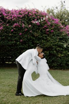 a bride and groom kissing in front of pink flowers