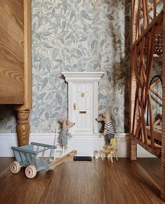 two stuffed animals sitting in front of a white door with blue and green wallpaper