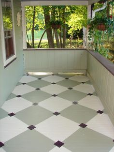 an empty porch with checkered tile flooring and potted trees in the background