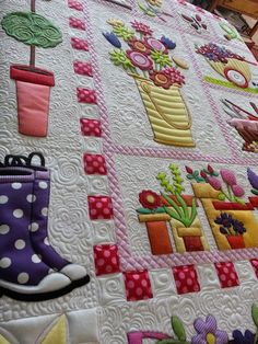 a quilted bed with flowers and rain boots on it