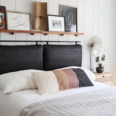 a bed with pillows and pictures on the wall above it, along with other items