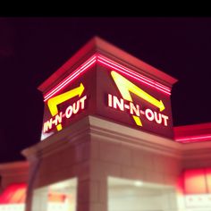 an in - n - out sign is lit up at night with red and yellow lights