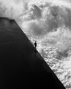 a person standing in front of a large wave