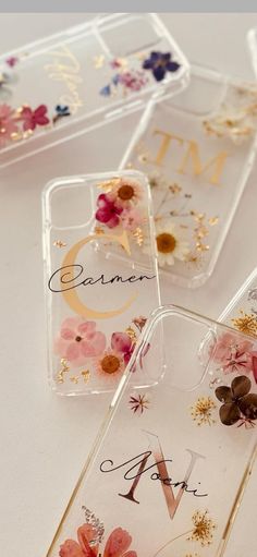 three clear cases with flowers on them sitting next to each other in front of a white table