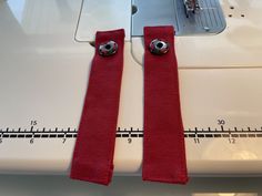 the sewing machine has two red ties on it's side and is next to a measuring tape