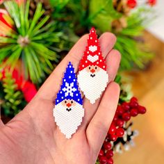 a hand holding two small christmas gnomes in red, white and blue