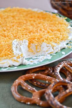 a cake with cheese and pretzels on the side sitting on a green plate