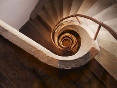 a spiral staircase in an old building with stone steps and wood handrails that lead up to the second floor