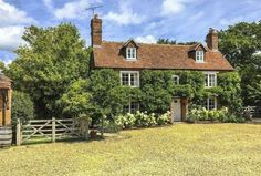 an old brick house surrounded by greenery and wooden fence in the country side yard