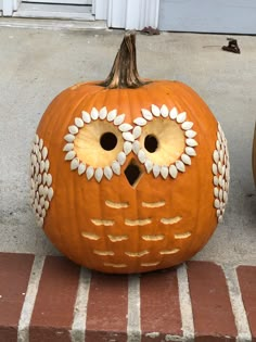 a pumpkin with an owl's face painted on it sitting in front of a door