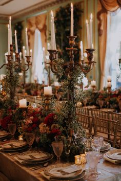 an elegant table setting with candles and flowers on the centerpieces for a formal function