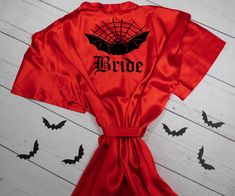 a red robe with the word bride written on it and bats flying in the background