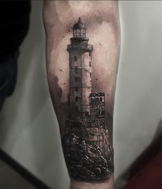 a man's arm with a lighthouse tattoo on it