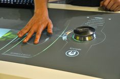 a person touching the touch screen on a table