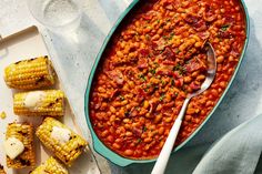 corn on the cob and baked beans in a blue dish with a spoon next to it