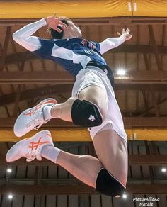 a man jumping up in the air to hit a volleyball ball with his racket