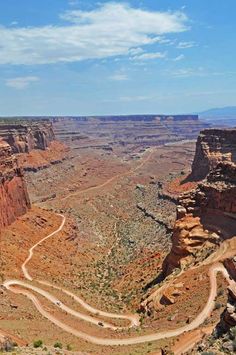 a scenic view of the grand canyon with a winding road in the foreground and mountains in the background