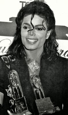 a black and white photo of a woman holding two trophies