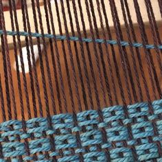 a close up view of some blue and brown weaves on a piece of wood