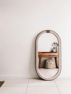 a mirror sitting on top of a white floor next to a wooden table and chair