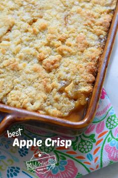 a casserole dish with apples and crumbs in it on a colorful cloth