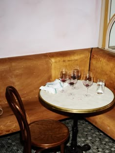 three wine glasses sitting on top of a table in front of a mirror next to a wooden bench