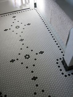 a bathroom with black and white hexagonal tiles on the floor next to a toilet