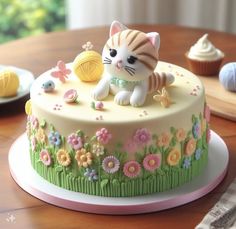 there is a cake decorated with a cat on top of the table next to cupcakes