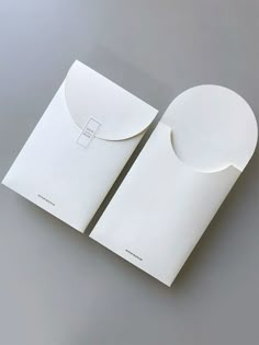 two white envelopes with one open and the other closed, on a gray surface