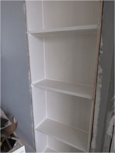 an empty white bookcase in the corner of a room that is being painted blue