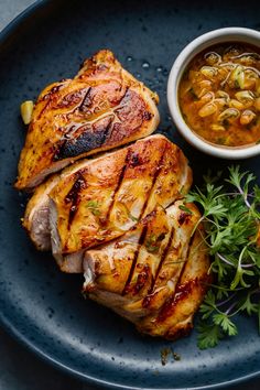 Grilled chicken breast with sauce and herbs on a dark plate. Lemon Herb