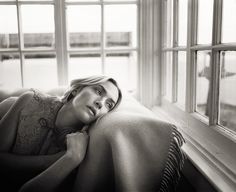 black and white photograph of a woman laying on the windowsill