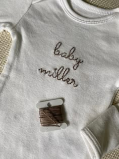 a white shirt with the words baby million written on it next to a spool of thread