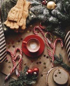 a cup of coffee on top of a table next to candy canes and christmas decorations