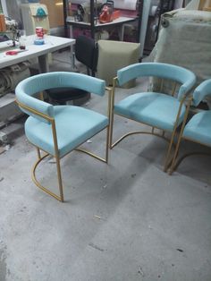 two blue chairs sitting next to each other on top of a floor in a room