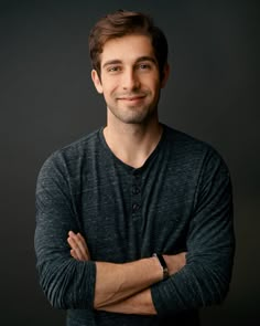 a man with his arms crossed smiling at the camera