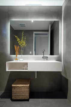 a white sink sitting under a bathroom mirror next to a wooden basket filled with flowers