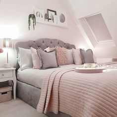 there is a bed with pink and gray pillows on it